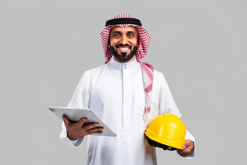 Engineer in traditional dress holding a tablet and yellow hard hat